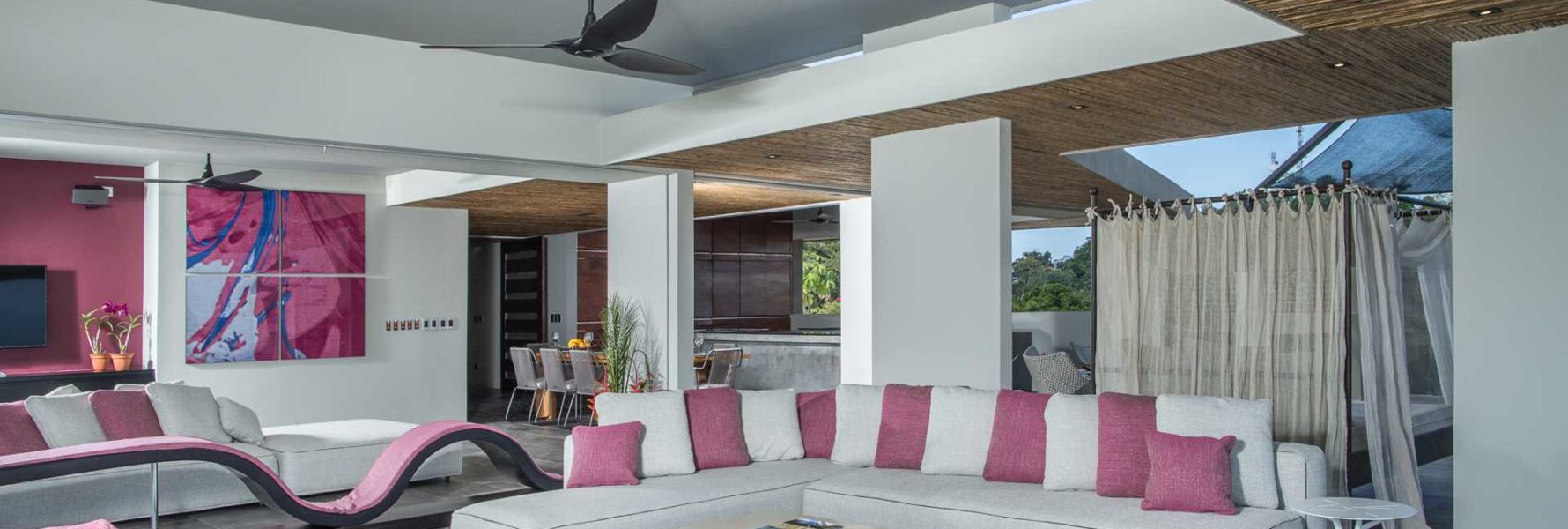The open-air main level has a large sitting area, dining room, and modern kitchen. This Manuel Antonio vacation villa has luxury appointments throughout. 