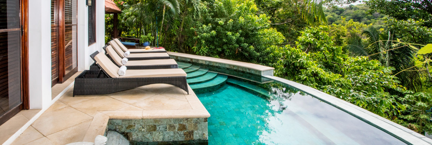 The recently renovated infinity pool is lined with stunning natural stone and has a deck with luxury recliners.