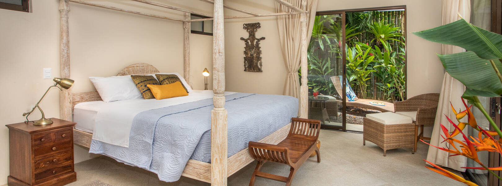 This large bedroom features a carved bleached wood king poster bed with sliding glass doors to the pool. 